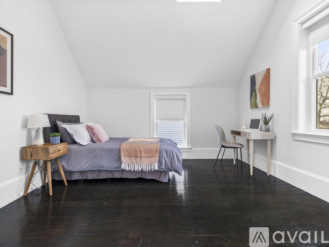 A bedroom with a bed, desk, chair, and window.