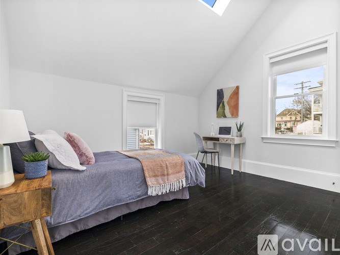 A bedroom with a bed, a chair, and a small table with a lamp on it.