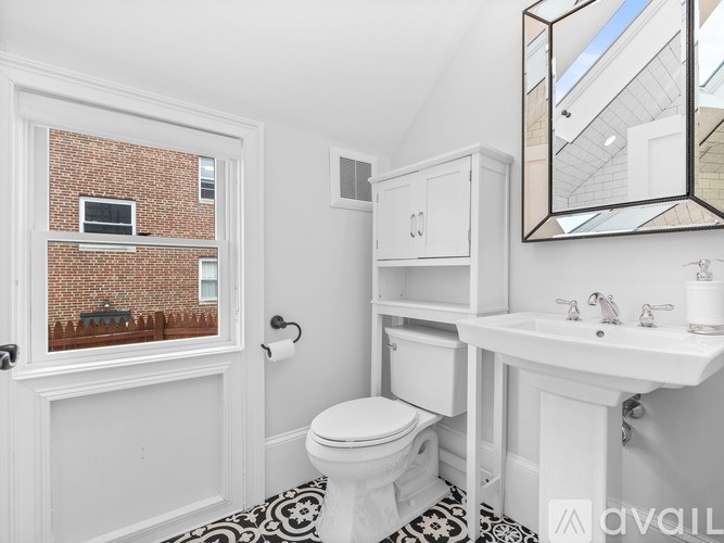 A bathroom with a toilet, sink, and mirror.