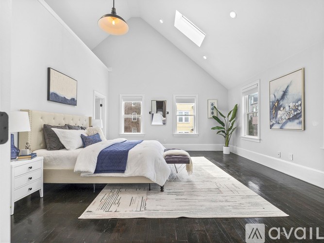 A bedroom with a large bed and a skylight.