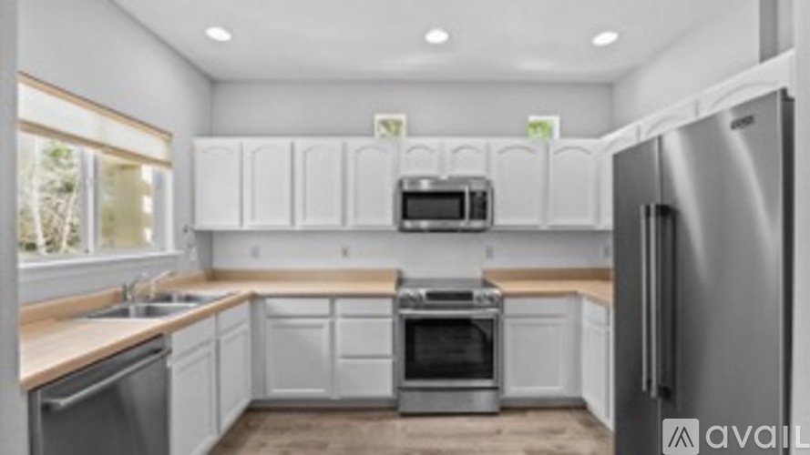 A modern kitchen with white cabinets and stainless steel appliances.