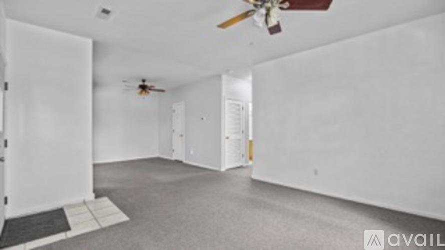 A spacious room with a ceiling fan and a door leading to another room.