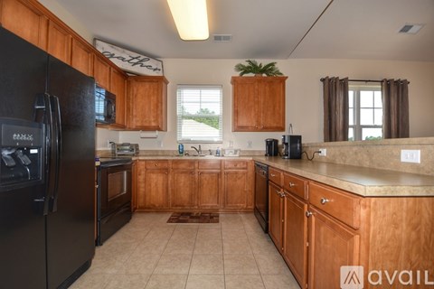 A kitchen with wooden cabinets and a black refrigerator.