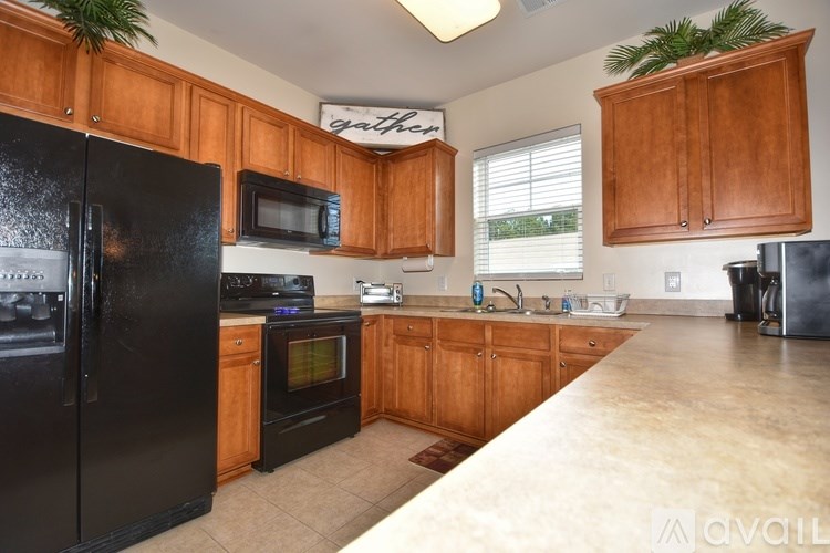 A kitchen with wooden cabinets and black appliances.