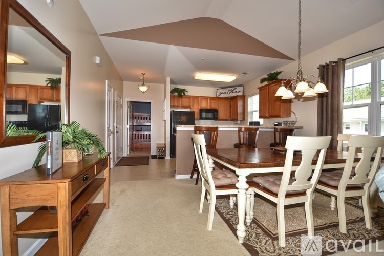 A well-lit, spacious kitchen and dining area with wooden furniture and a large mirror.