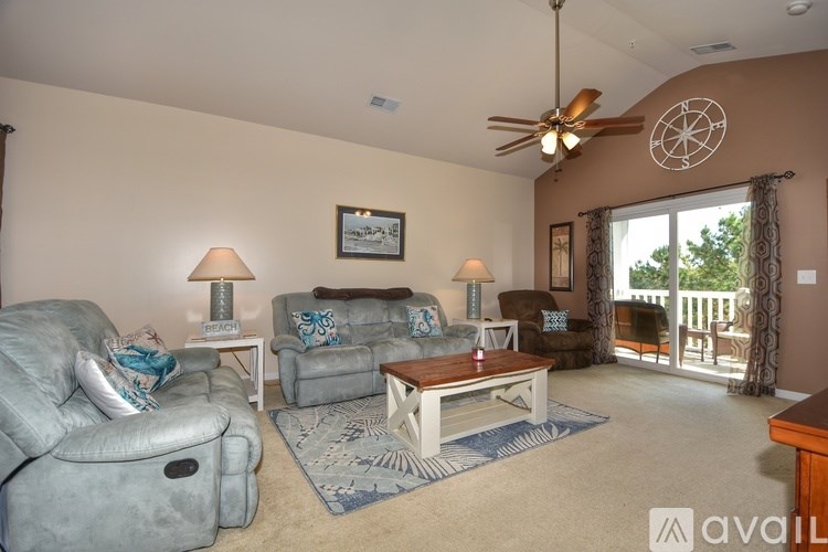 A living room with a grey couch, a brown table, and a ceiling fan.