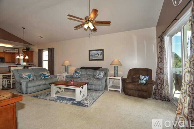 A living room with a ceiling fan and a brown armchair.