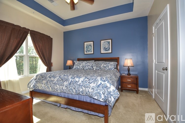 A bedroom with a bed, two lamps, and two pictures on the wall.