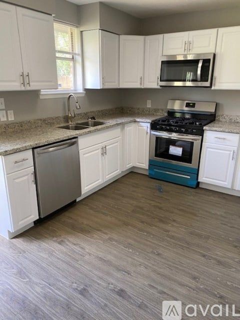 A kitchen with white cabinets and a wooden floor.