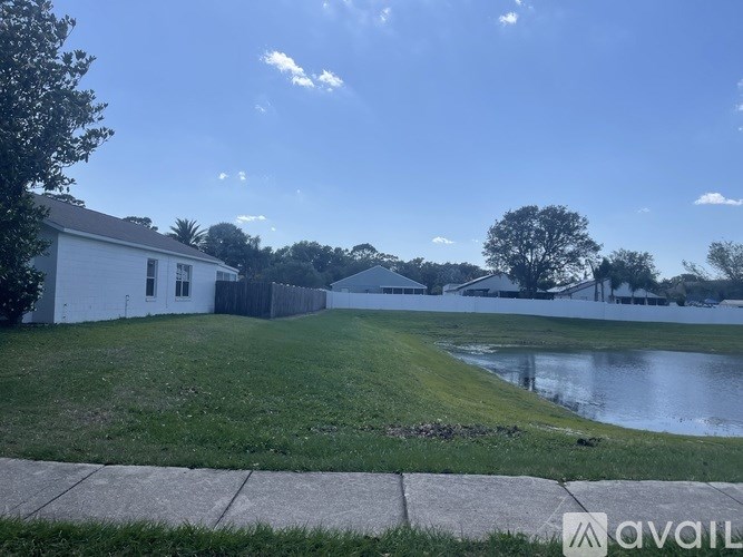A house with a yard and a pond in front.