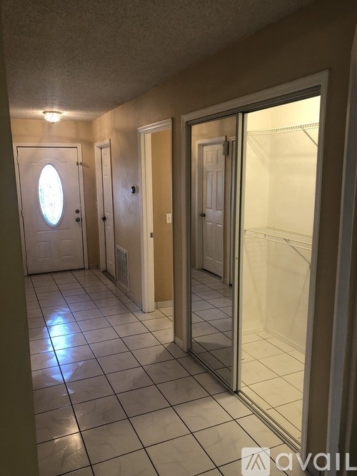 A hallway with a glass door leading to a bedroom.