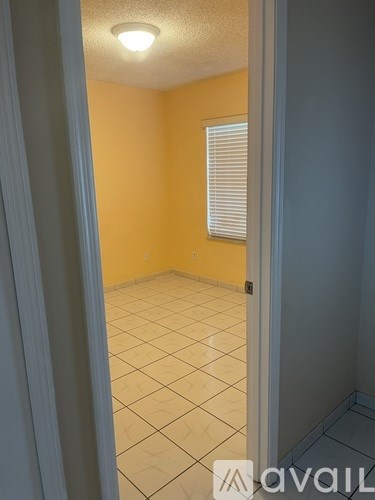 A room with a tiled floor and a window with blinds.