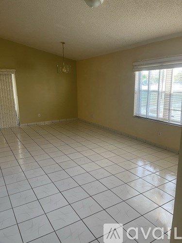 A room with a white tile floor and a window with blinds.