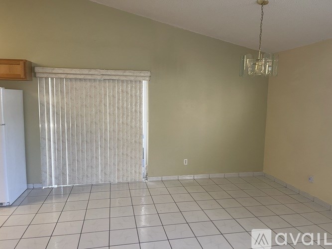 A room with a white tile floor and a window covered with white blinds.