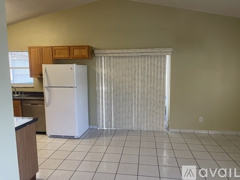A kitchen with a white refrigerator and a white tiled floor.