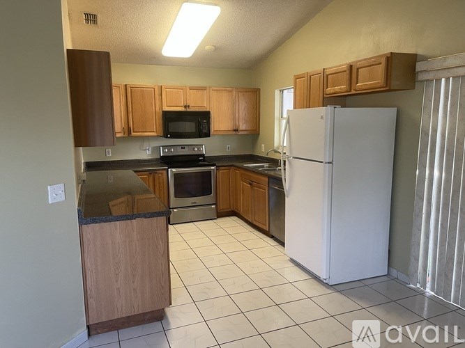 A kitchen with a white refrigerator, wooden cabinets, and a black countertop.