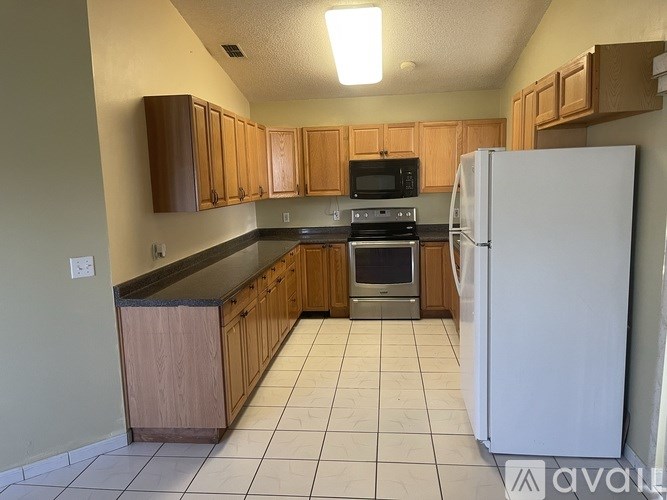 A kitchen with a white refrigerator, wooden cabinets, and a black countertop.