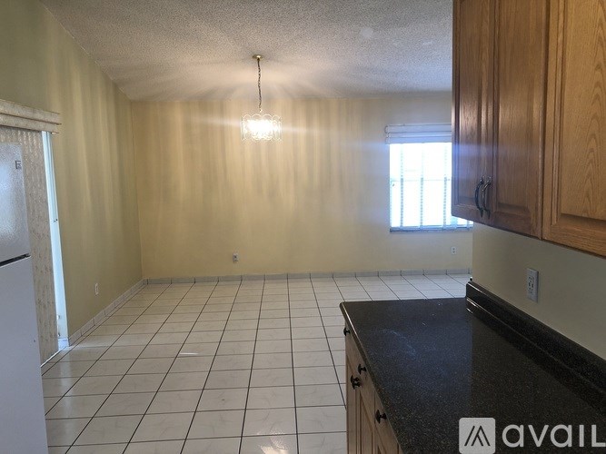 A kitchen with a black countertop and white tile floor.