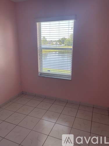 A room with pink walls and a window with blinds.