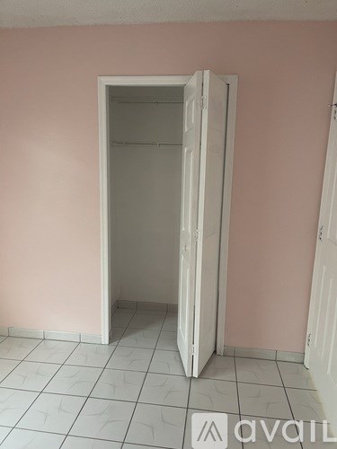 A white door is open in a room with pink walls.