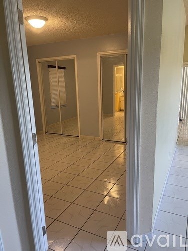 A hallway with a tiled floor and white walls.