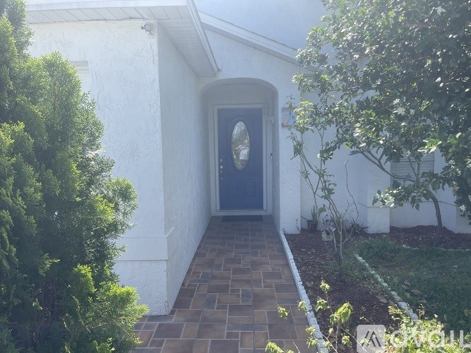 A white house with a blue door and a brick pathway leading to it.
