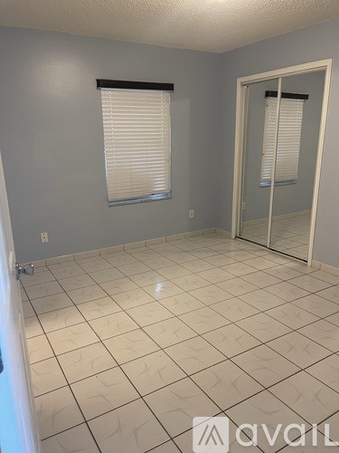 A room with white tiled flooring and a glass door.