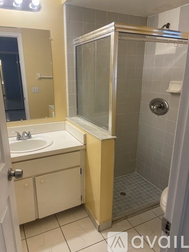 A bathroom with a sink, mirror, and shower.