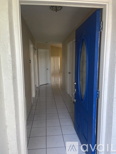 A hallway with a blue door and white walls.