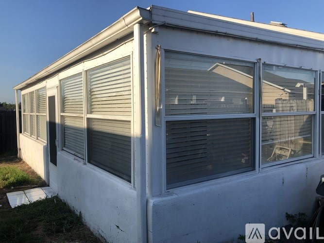 A white house with a grey roof and a window with blinds.