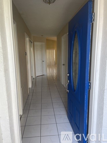 A long hallway with a blue door at the end.