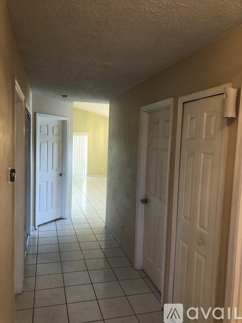 A hallway with white doors and tiled floors.
