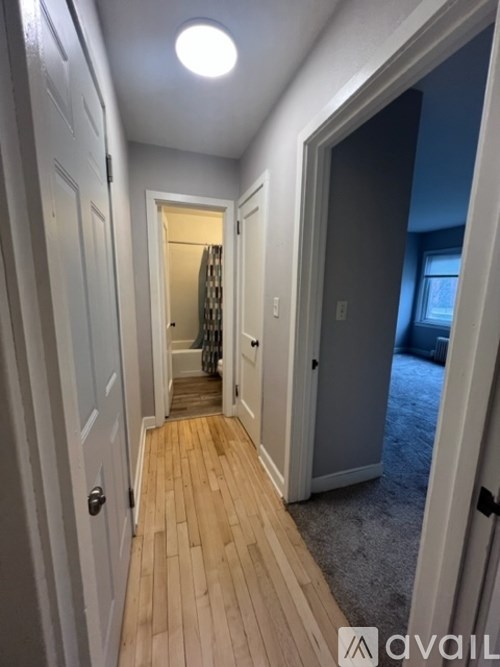 A hallway with wooden floors and white walls.