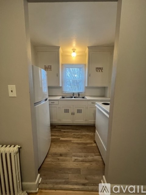 A kitchen with white cabinets and a wooden floor.