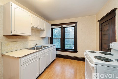 A kitchen with white cabinets and a white stove top oven.