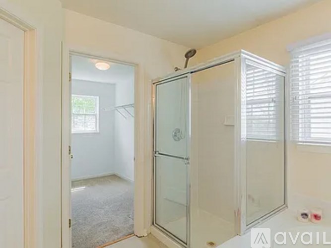 A bathroom with a glass shower door and a white door.