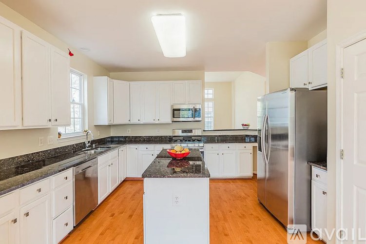 A kitchen with white cabinets and a black countertop.