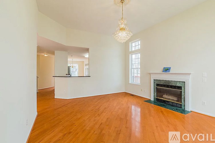 A large empty room with a fireplace and a chandelier.