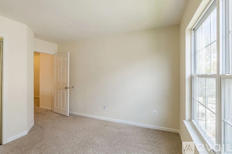 A room with a carpet floor and a door leading to another room.