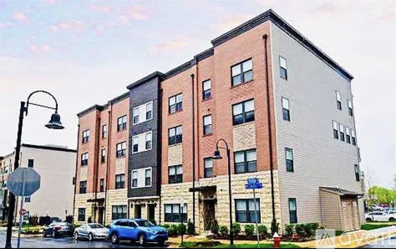 A street view of a multi-story apartment building with cars parked in front.