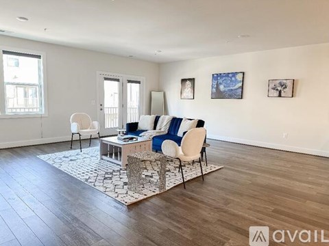 A living room with a white chair, a white sofa with blue and white cushions, a white coffee table, and a white rug with a black and white pattern.