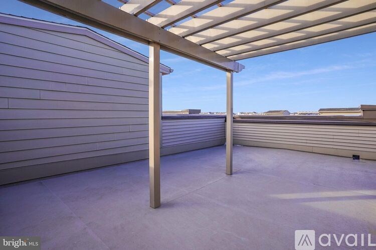 A patio with a white pergola and a concrete floor.