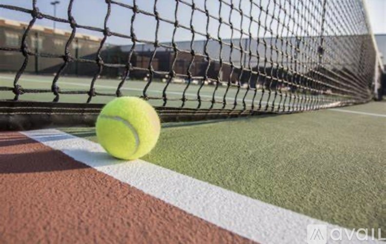 A tennis ball is on the ground near the net.