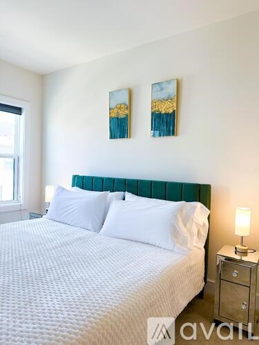 A bedroom with a large bed and two paintings on the wall.