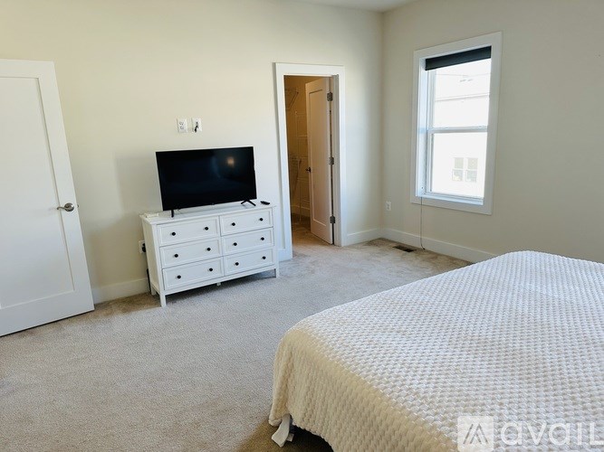 A bedroom with a bed, dresser, and television.