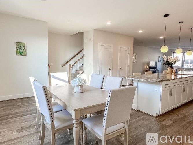 A dining room with a table set for four and a kitchen in the background.