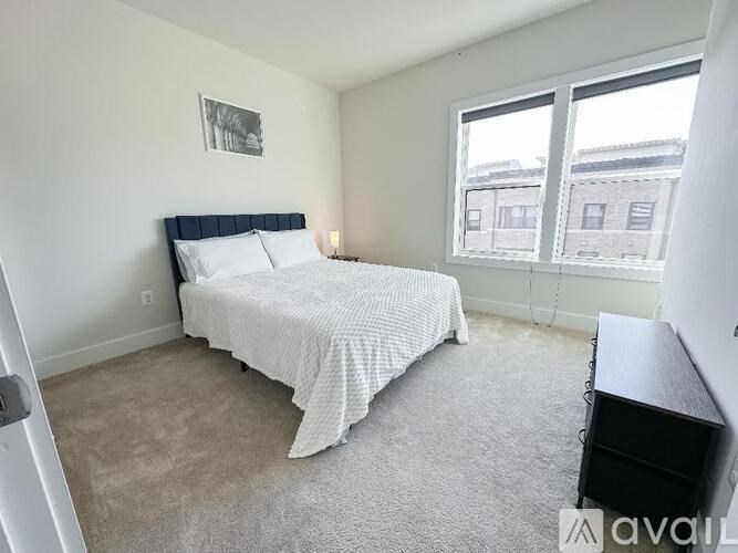 A bedroom with a bed, desk, and window.