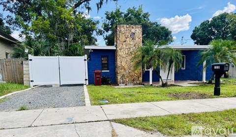 A blue house with a white fence and a red trash can.