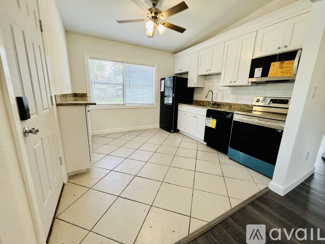A kitchen with white cabinets and black appliances is available for rent.