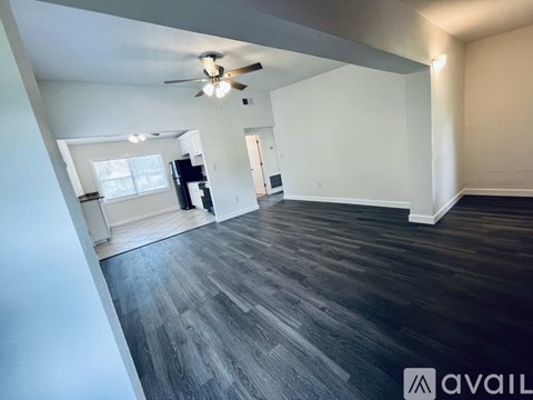 A spacious room with a ceiling fan and wooden flooring.